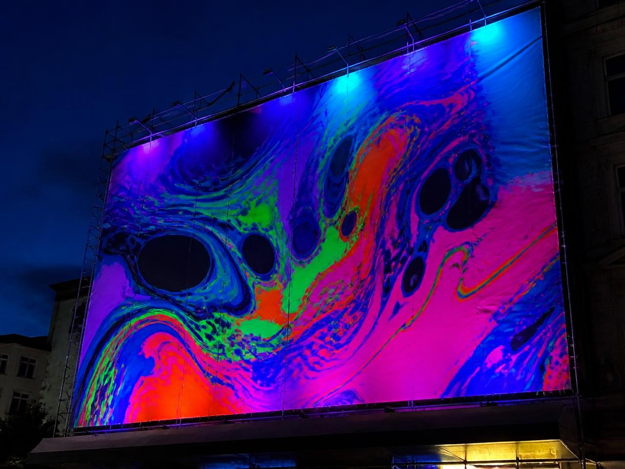 Samme banner om aftenen, hvor farverne gløder under UV-lys